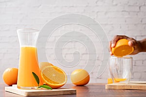 Jarra de fresco impreso naranja jugo hombre mano apretando naranja agregado azúcar 