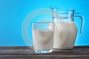 Jug and glass with milk on a wooden table