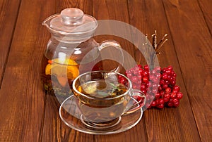 A jug with hot tea and bunch of viburnum from colds