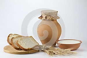 Jug of milk with freshly baked white bread and wheat ears