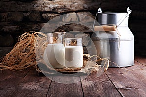 A jug of milk and glass of milk on a wooden table.