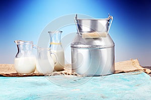 A jug of milk and glass of milk on a wooden table