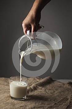 A jug of milk and a glass in a rustic style on a burlap tablecloth,,