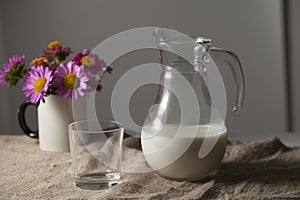 A jug of milk and a glass in a rustic style on a burlap tablecloth,,