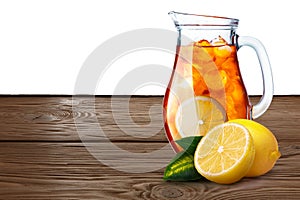 Jug or pitcher of iced tea with lemons on foreground standin on