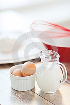 Jugful of milk, eggs in a bowl and flour