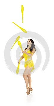 A juggler, a circus performer, a young woman in a yellow suit with dark hair, performs on a white background