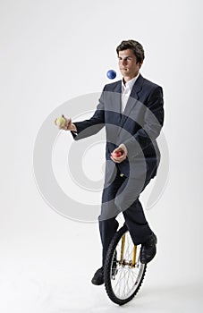 Juggling businessman on unicycle