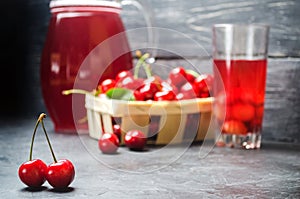 Juice or compote with cherries. fresh ripe red cherry in a basket on a gray concrete background, summer berry, space for text