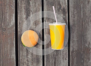 juice cup and hamburger on a wooden table or floor background