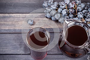 Juice in jug and glass, black grapes top view