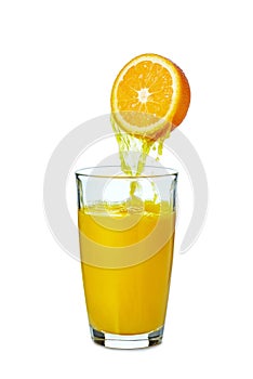 Juice pouring from orange fruit to glass on white