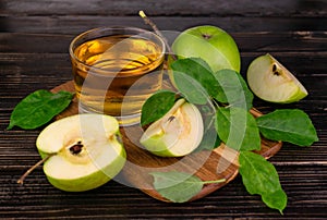 Juice from ripe green apples in a glass on a wooden background.