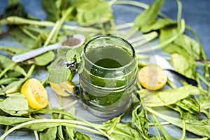 Juice of Spinach,Spinacia oleracea or paalak with sliced lemons,Citrus Ã— limon on a silver wooden surface.