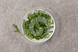 Juicy arugula on a white plate, top view
