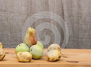 Juicy autumn pears and green apples are arranged on a wooden rustic table in a farmhouse.