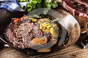 Juicy beef Rib Eye steak roasted potatoes with sauce grilled vegetable salt pepper and herbs in vintage pan