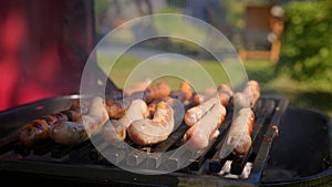 Juicy beef sausages are cooked over an open fire in summer weather. Grilled pork and beef sausages are cooked over hot