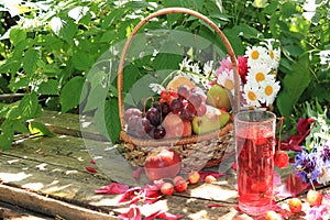 Juicy black grapes and apples, pears and peaches in a basket in the garden on an old wooden table,