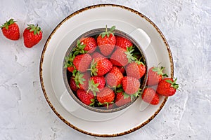 Juicy, bright and sweet strawberries in a bowl on a white concrete table