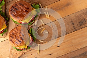 Juicy burgers with beef, cheese, lettuce, onions, tomatoes, cucumbers, buns and sauce cooked on a grill. Cheeseburger on a wooden