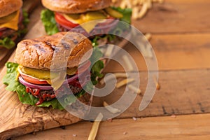 Juicy burgers on a wooden background with french fries. Home recipes, or cafe. Calorie and junk food