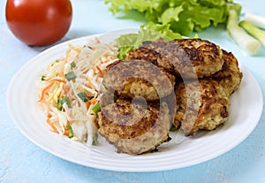 Juicy cutlets and salad with fresh vegetables: cabbage, carrots, greens