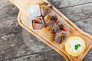 Juicy delicious meat cutlets and hominy or Corn porridge Polenta with goat cheese on cutting board on wooden background