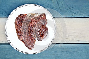 Juicy Delicious thick grilled T-bone beef steak viewed from above. Flag of Argentina background