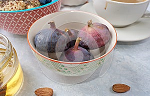 Juicy figs in a green bowl on a blue table