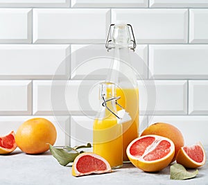 Juicy and fresh grapefruit and bottle juice on a blue table on  a white brick background. Concept healthy and diet  food. Front