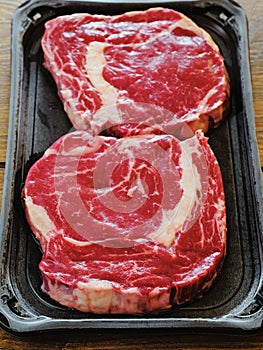 Juicy fresh raw rib eye steak on a plastic trey.