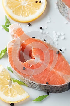 Juicy fresh salmon steak in a white plate with onion lemon and spices