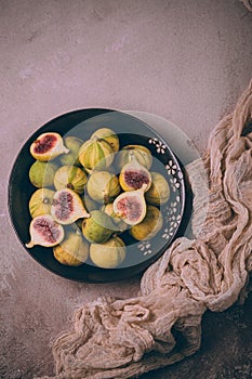 Juicy fresh tiger figs in bowl on dust pink table
