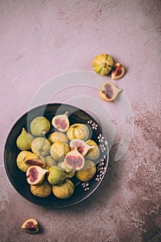 Juicy fresh tiger figs in bowl on dust pink table