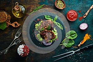 Juicy fried pork steak with spices on a black stone plate.