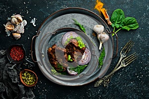 Juicy fried pork steak with spices on a black stone plate.