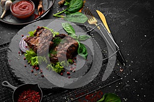 Juicy fried pork steak with spices on a black stone plate.