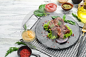 Juicy fried pork steak with spices on a black stone plate.