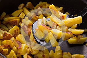 Juicy fried potatoes in a frying pan, homemade roasted potatoes with a crispy crust close up.