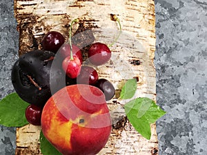 Juicy fruits: peach, cherry and plum on the bark of birch trees in a summer day. summer freshness