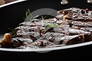 Juicy and grilled beef Rib Eye steak in pan with salt, pepper and rosemary herbs