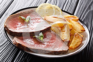 Juicy grilled beef steak with roasted potatoes and lemon close-up on a plate. horizontal