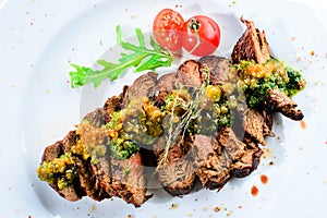 Juicy grilled beef steak with sauce pesto in a white plate, top