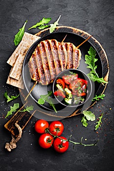 Juicy grilled chicken meat lula kebab on skewers with fresh vegetable salad on black background