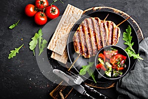 Juicy grilled chicken meat lula kebab on skewers with fresh vegetable salad on black background