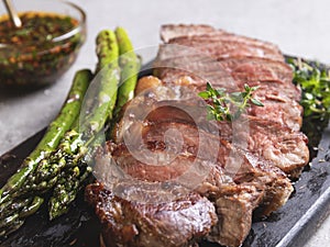 Juicy, grilled, sliced beef steak, with roasted asparagus, close up, sauce