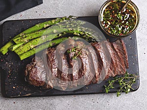 Juicy grilled sliced beef steak, with roasted asparagus, close up, sauce, wooden board