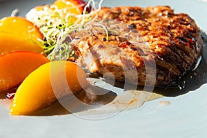 Juicy grilled turkey steak with caramelized peach. Closeup.
