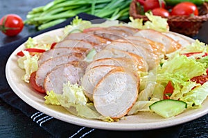 Juicy home made sausage with a light spring salad of fresh vegetables on a black wooden background.